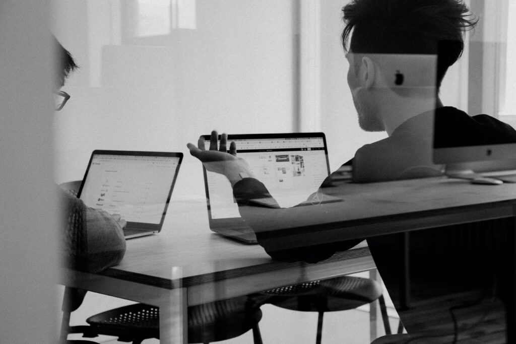Deux personnes travaillant sur un bureau avec des ordinateurs